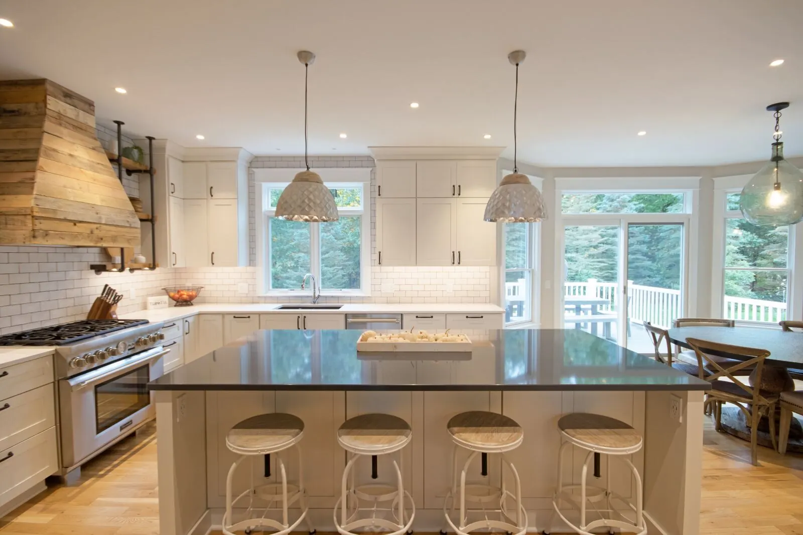 White kitchen with a reclaimed wood range hood and a large island with stools