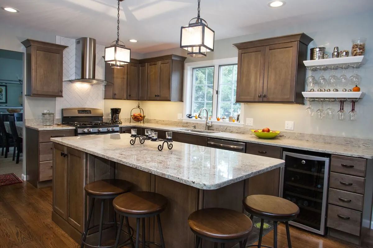 Kitchen in brown stained cabinets with a granite island and lantern pendants