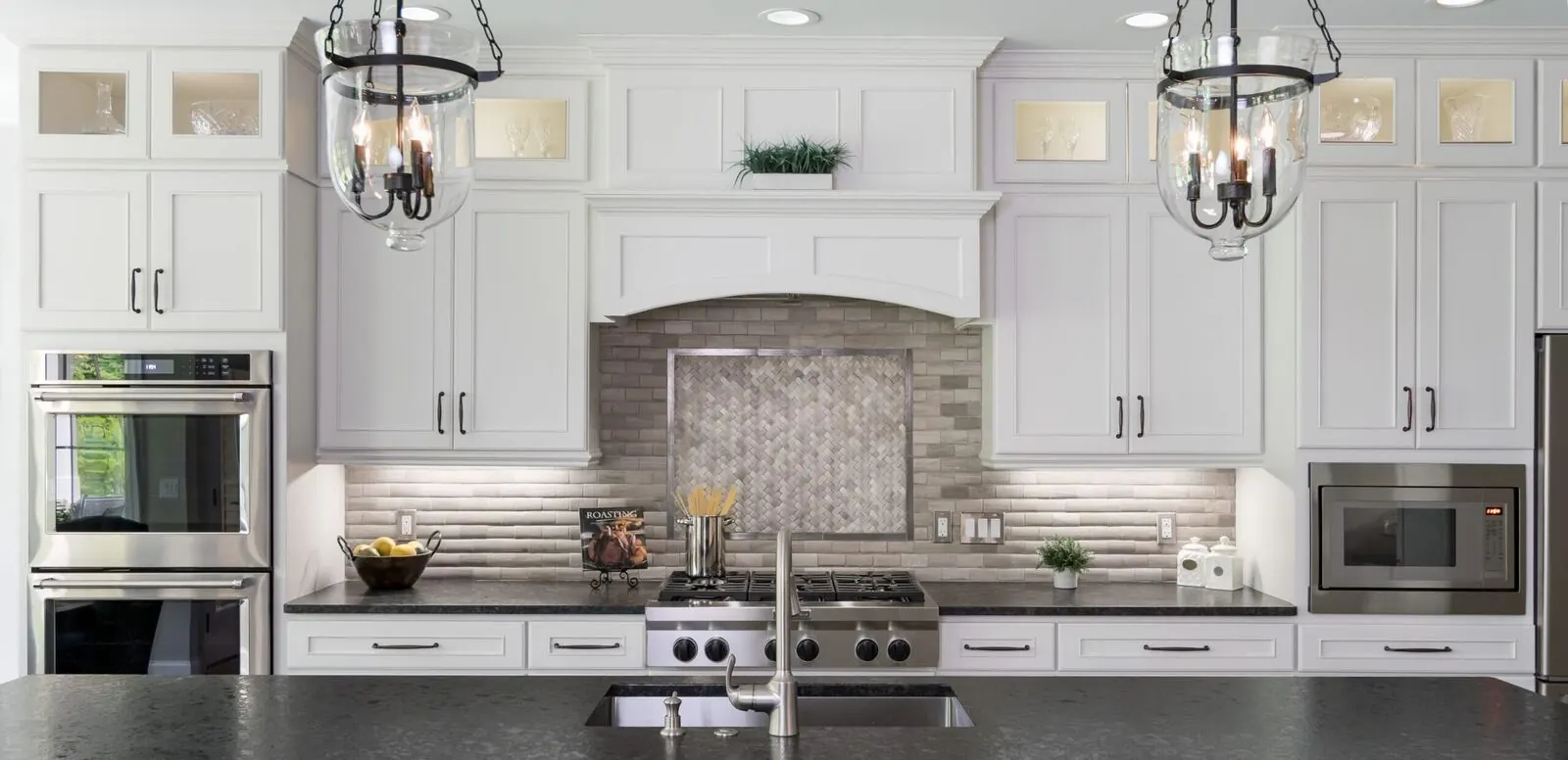 White kitchen with glass-front uppers, a tile backsplash and a long island