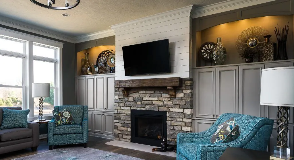 Family room with gray built-in cabinets around a stone fireplace and TV